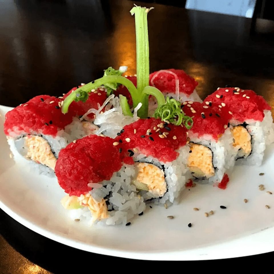 Sushi Nori's sushi rolls with red tuna, sesame seeds, and green garnish on a white plate.
